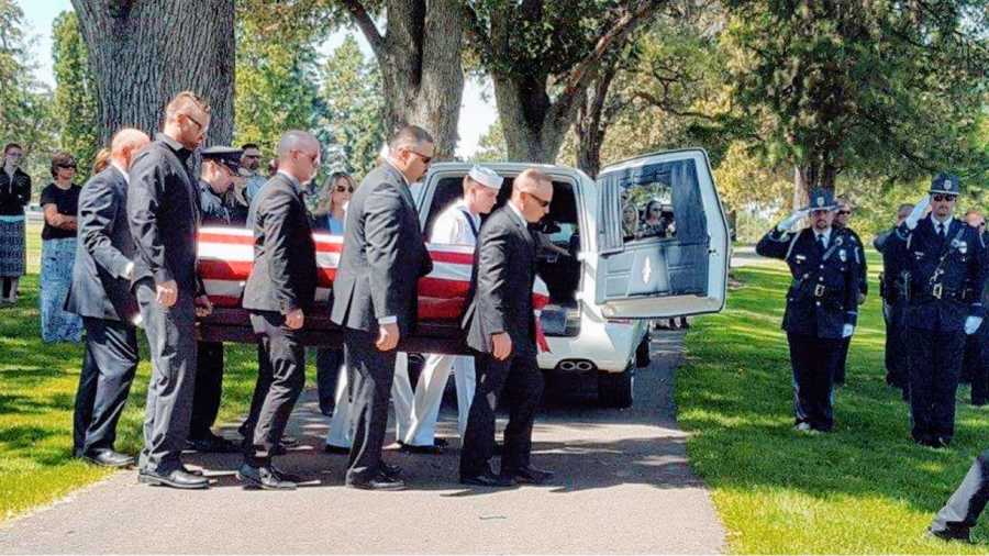 Widow takes a photo of men carrying her late husband's casket
