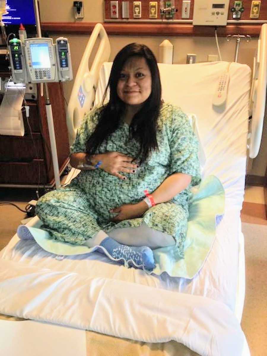 woman in hospital bed holding pregnant stomach