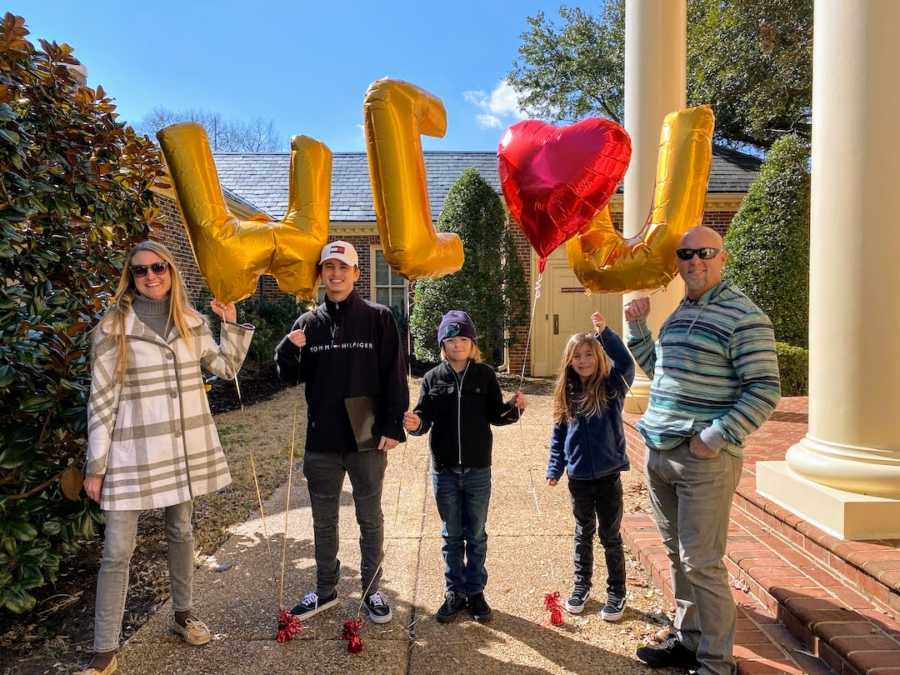 family holding "we love you" balloons