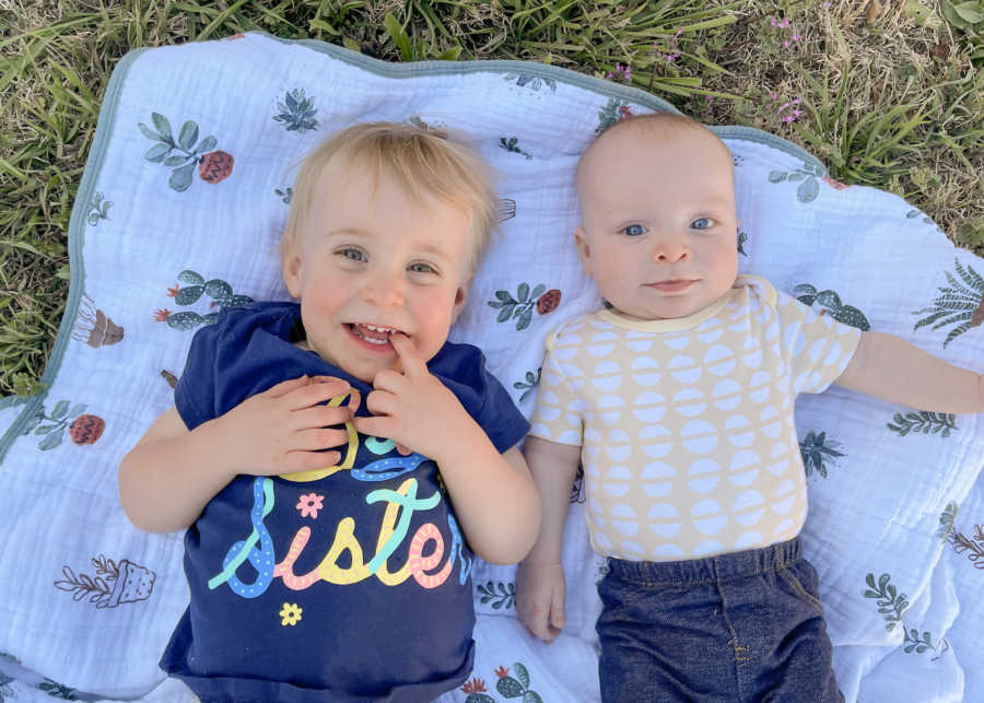 2 kids laying on a blanket