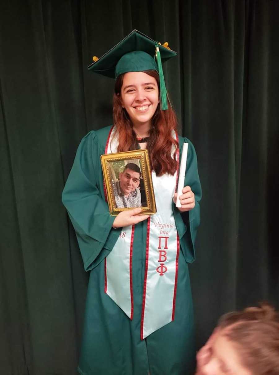 girl in cap and gown holding photo of dad