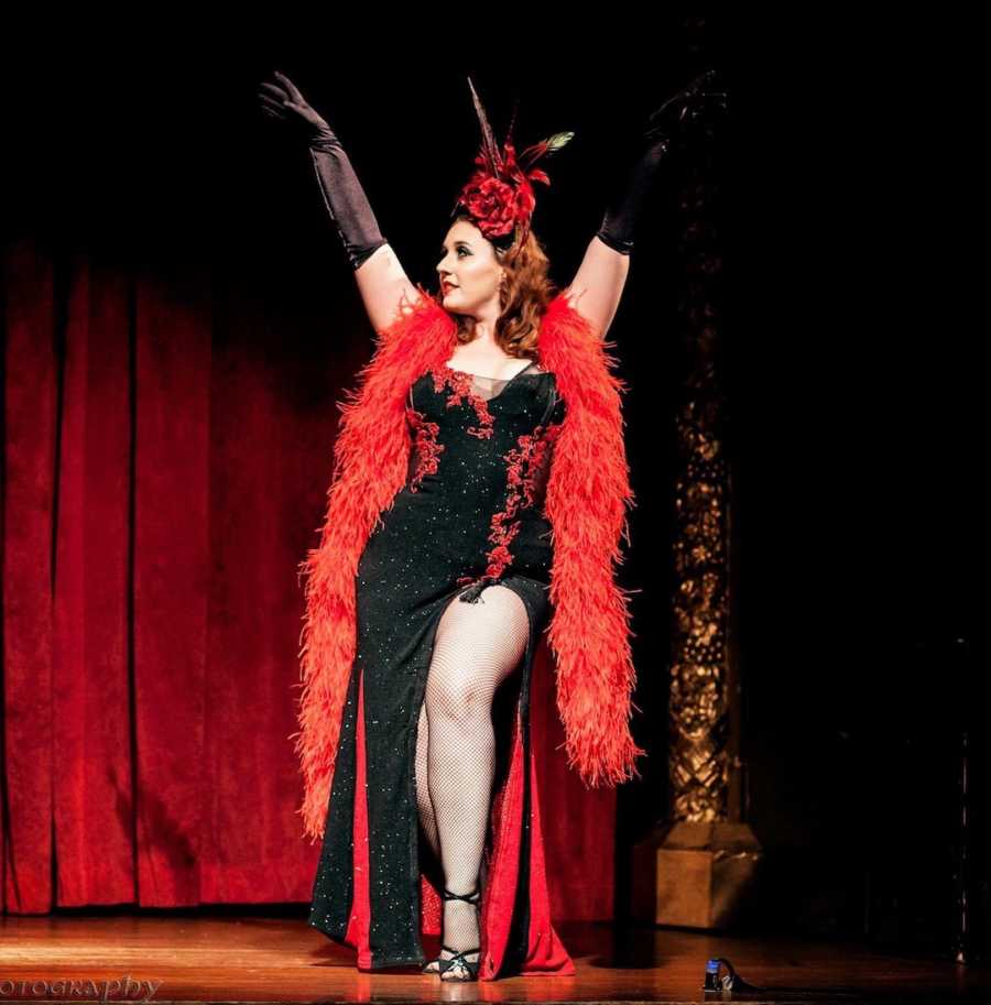 woman in burlesque show wearing a black and red dress with feather boa