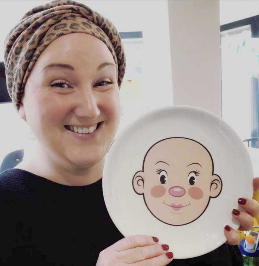 bald woman with a plate with a bald head painted on it