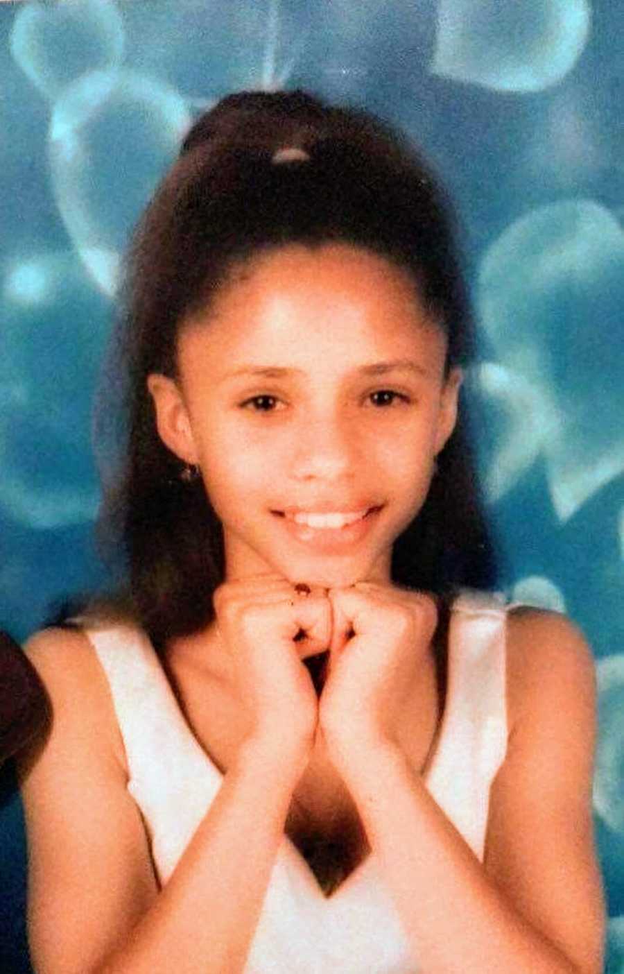 Young girl poses for a school photo with a blue background