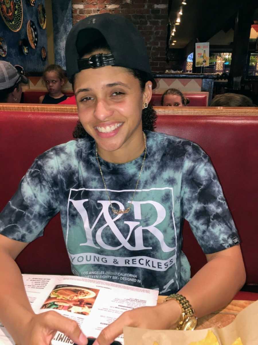 Lesbian smiles for a photo while out at a restaurant in a Young & Reckless t-shirt