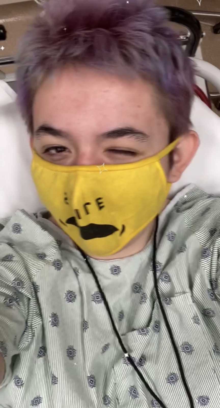 teen in hospital scrubs and yellow mask winking