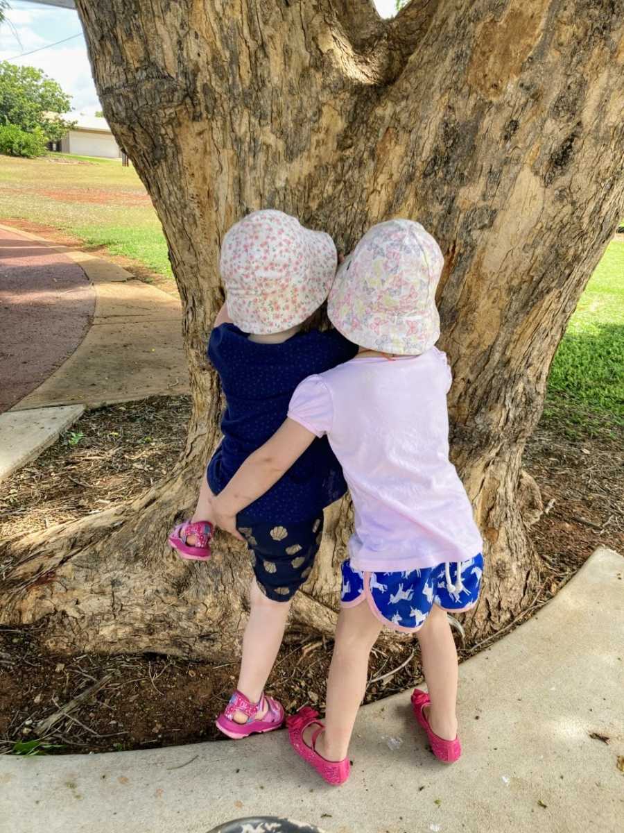 Mom snaps photo of twin sisters helping each other climb up a tree