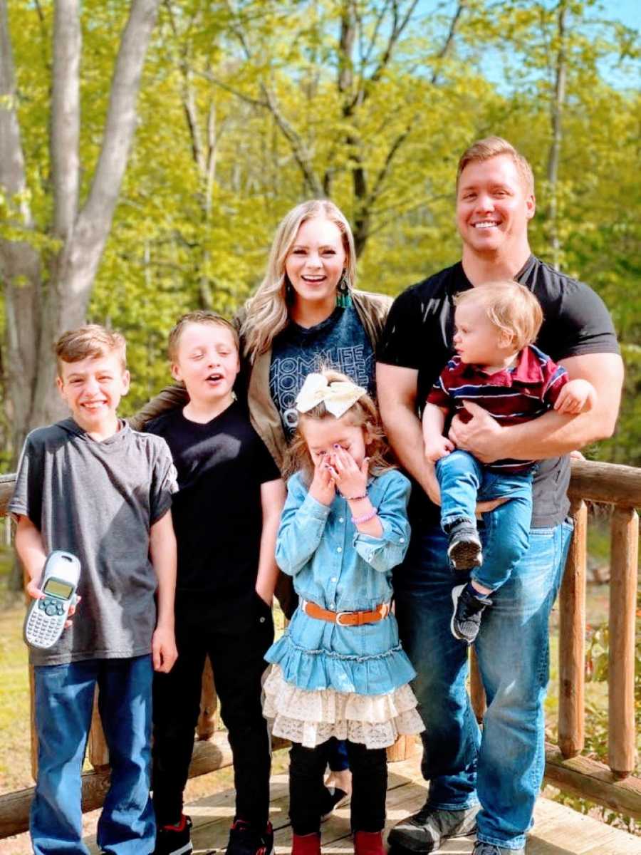 Young family of six take a candid family photo together on the back porch of their dream home