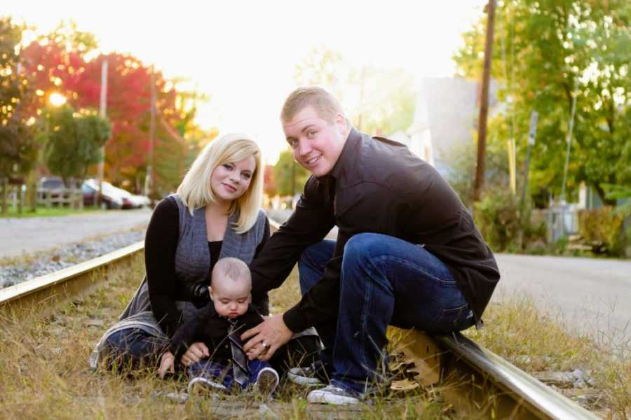 Young Christian married couple take photos on railroad tracks with their infant son