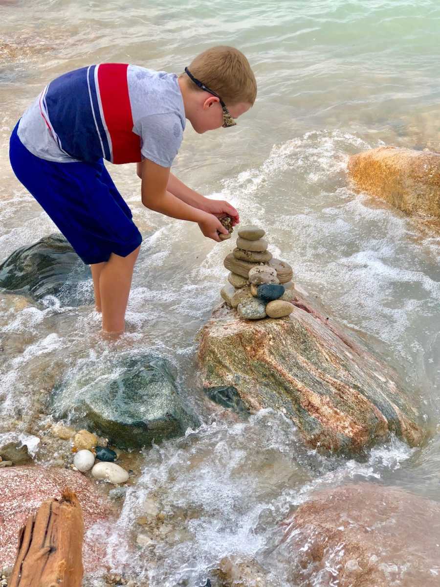 boy stacking rocks at the beach