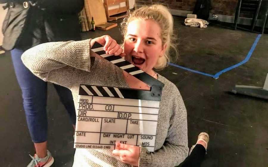 A young woman at university with a clapboard