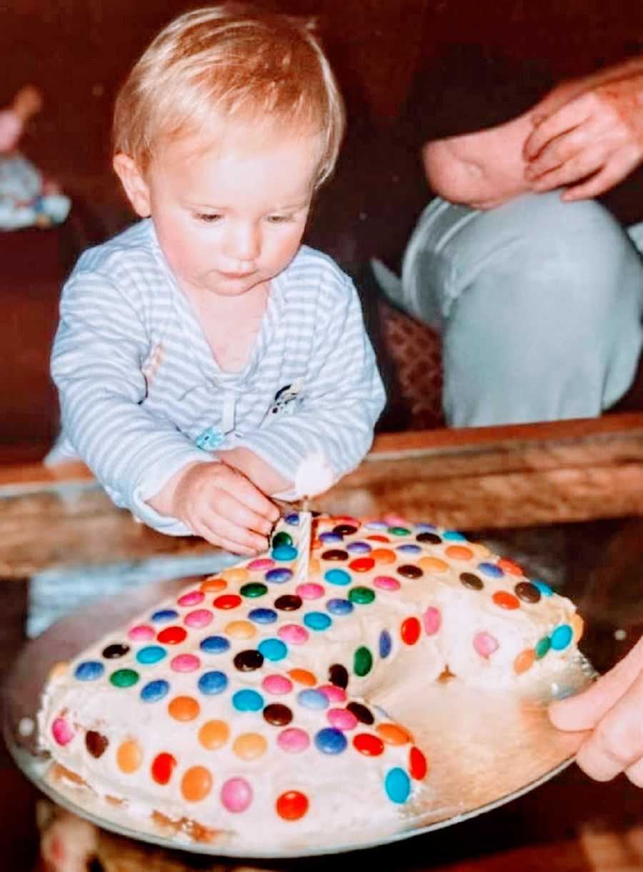 A little girl sitting by a birthday cake