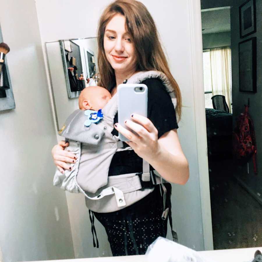 Mom takes mirror selfie with her newborn son napping while strapped to her chest