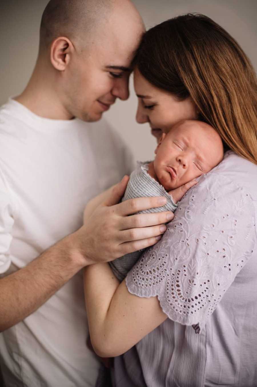 First time parents take beautifully intimate family photo with newborn son in postpartum photoshoot