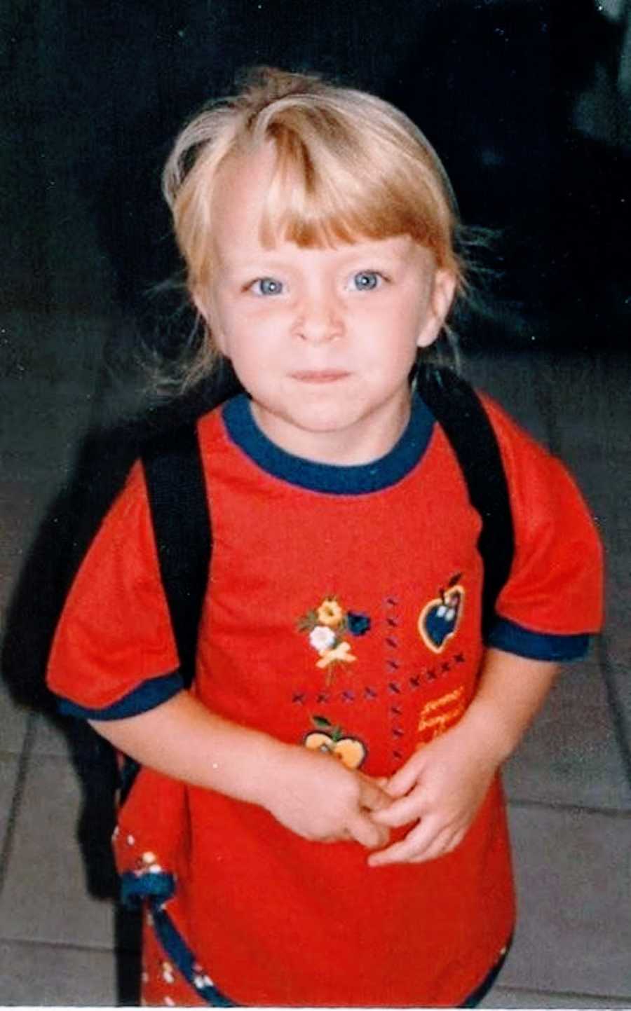 Young girl with blonde hair and blue eyes makes a silly tough face at the camera