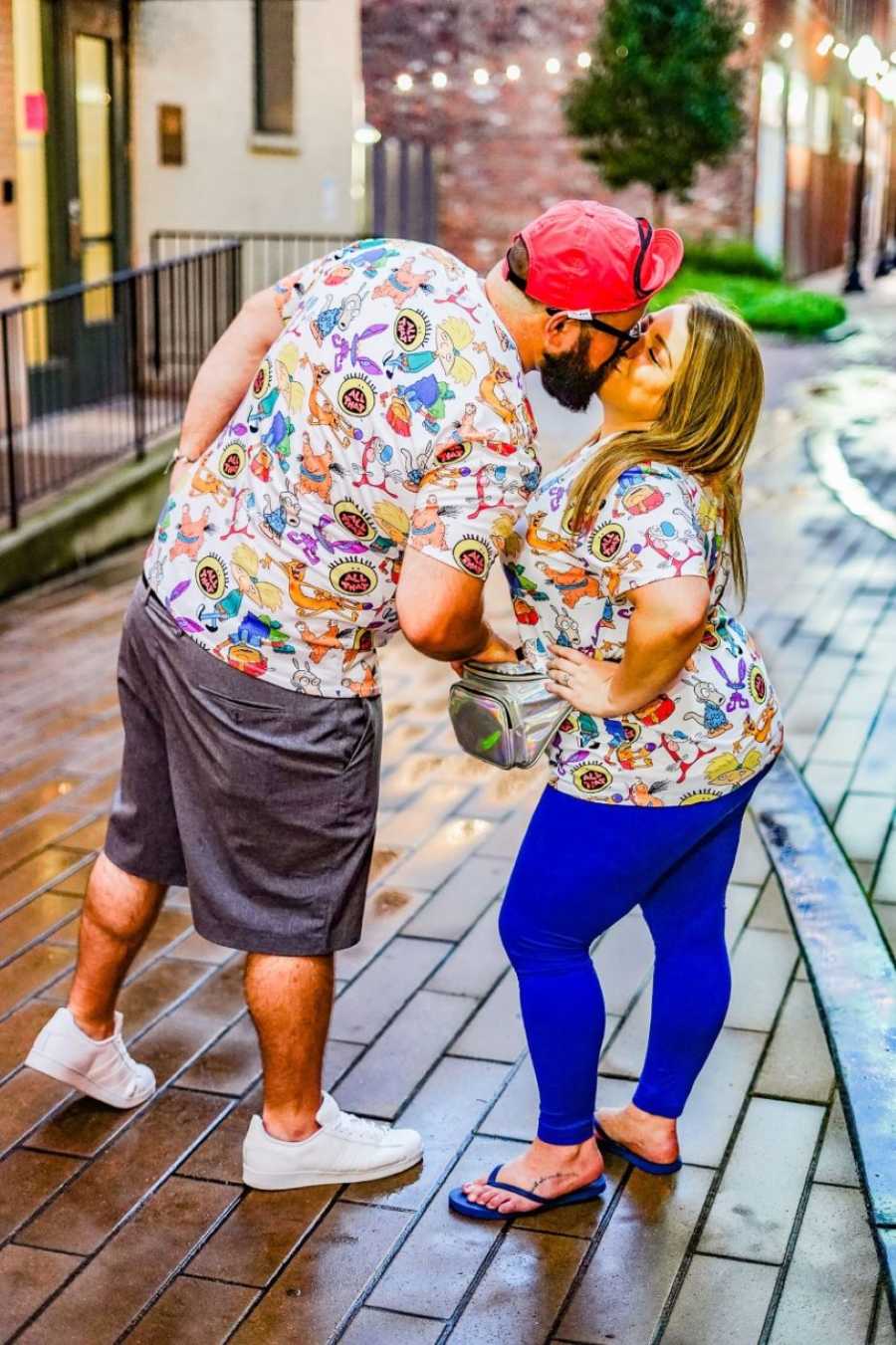 Couple share a sweet kiss while wearing matching 90's t-shirts