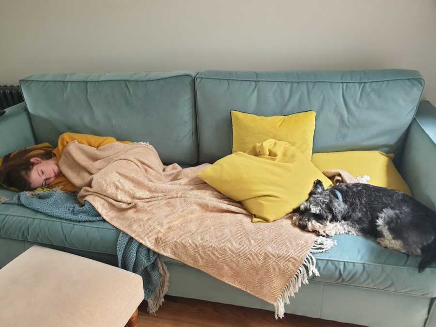 young girl laying on the couch with a dog