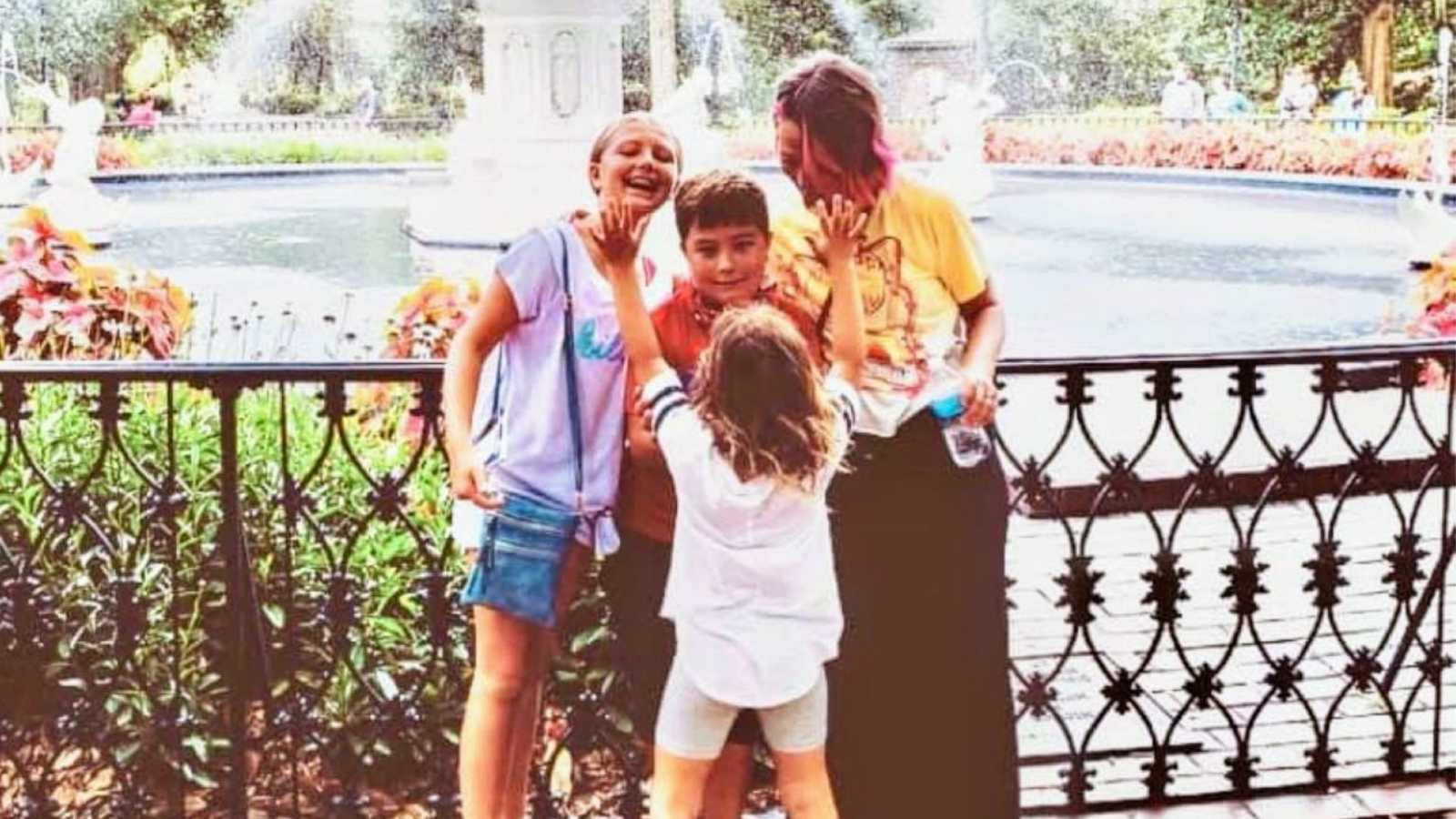 Mom takes a candid photo in front of a fountain with her three children