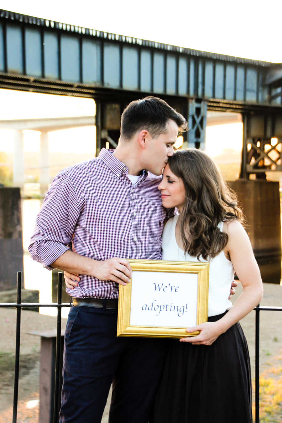 couple holding "we're adopting" sign