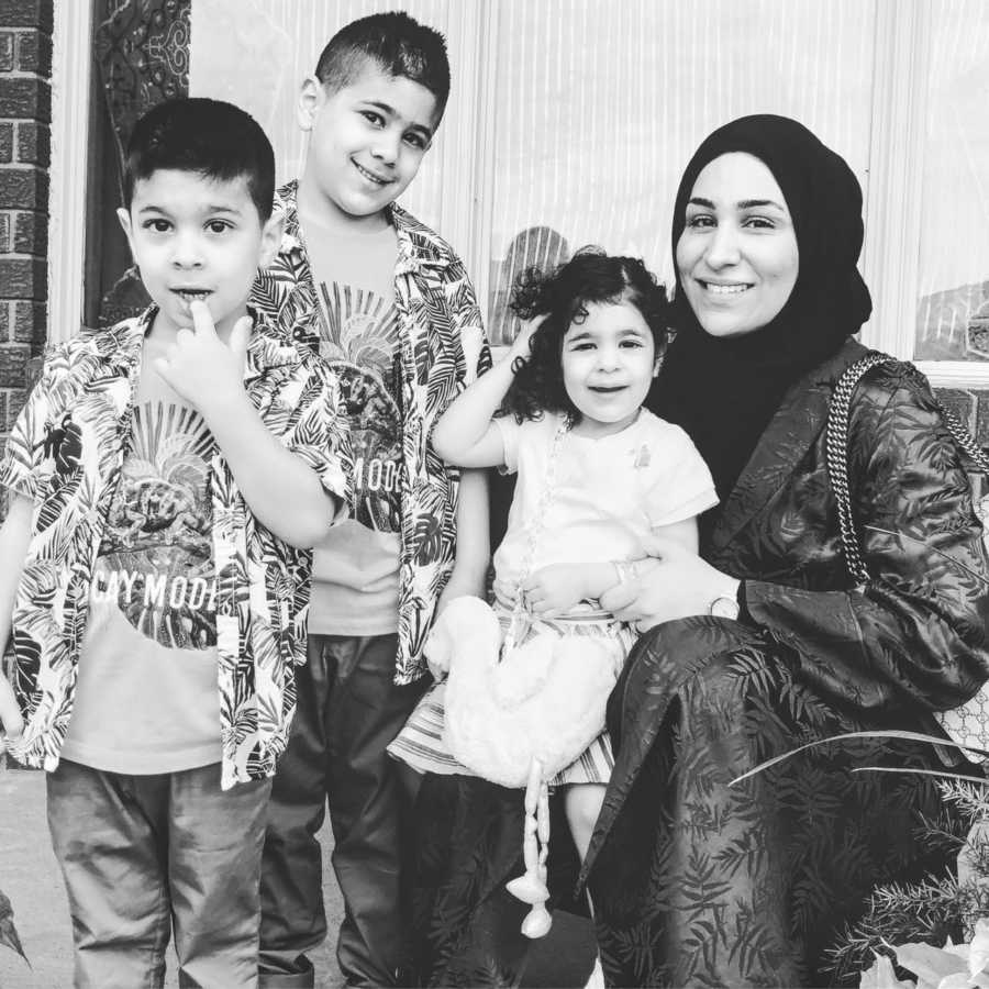 Mom takes photo with her three children while holding her daughter on the porch