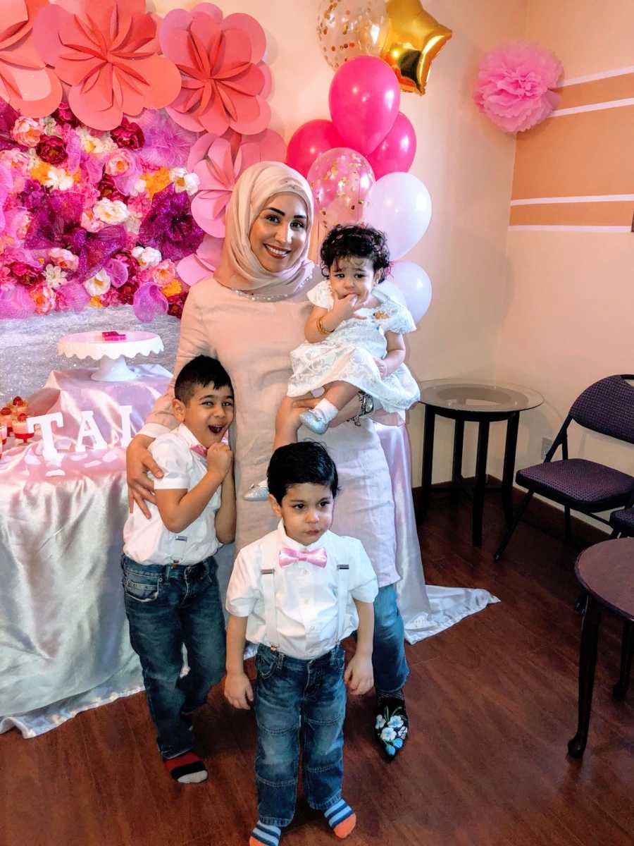 Mom takes a photo with her three children at her daughter's pink-themed birthday party