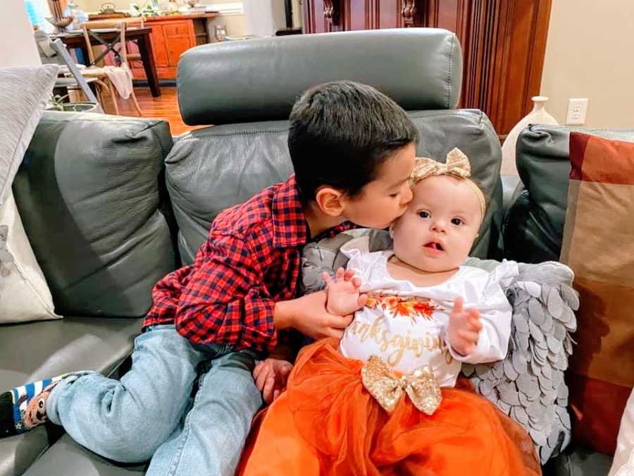 A little boy kisses his baby sister on the cheek