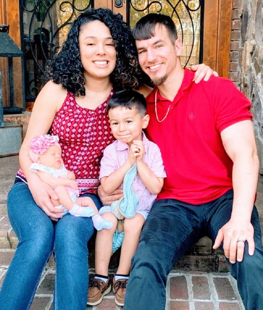 Parents sit with their two children on porch steps