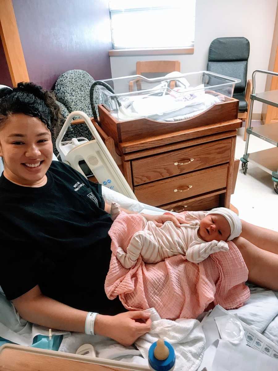 A mother sits in the hospital with her newborn baby girl