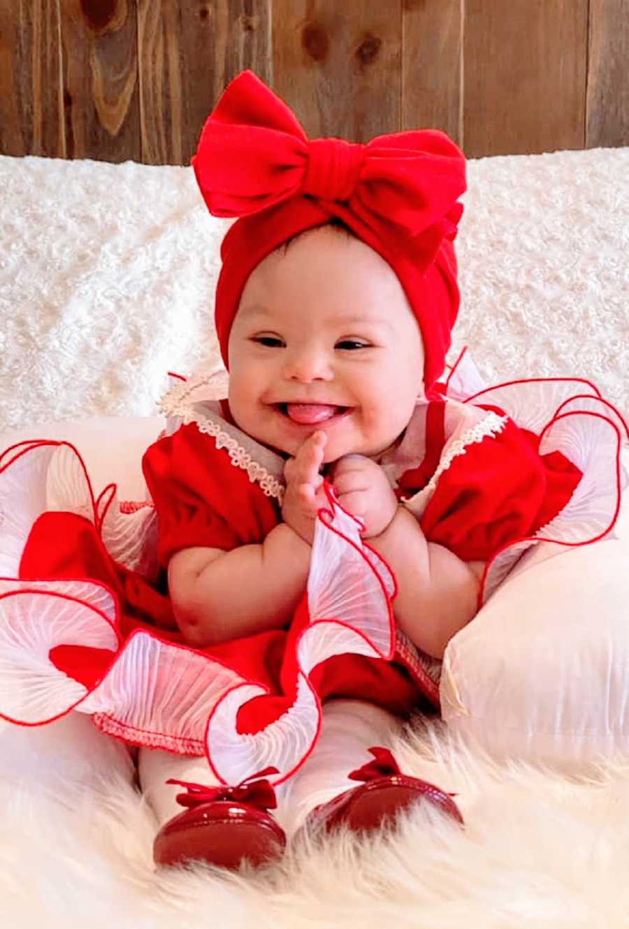 A little girl wearing a red dress and bow