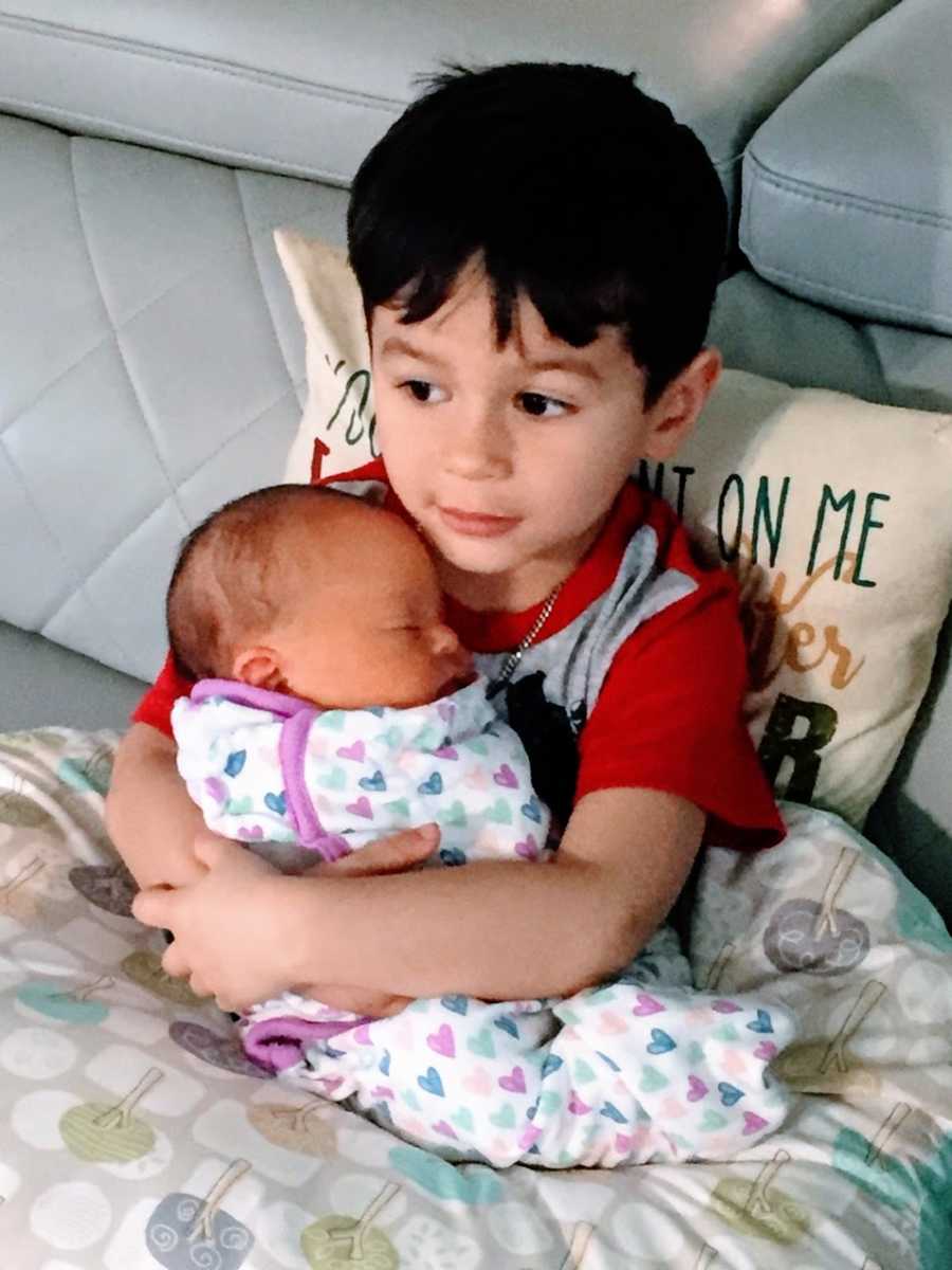 A little boy holds his baby sister