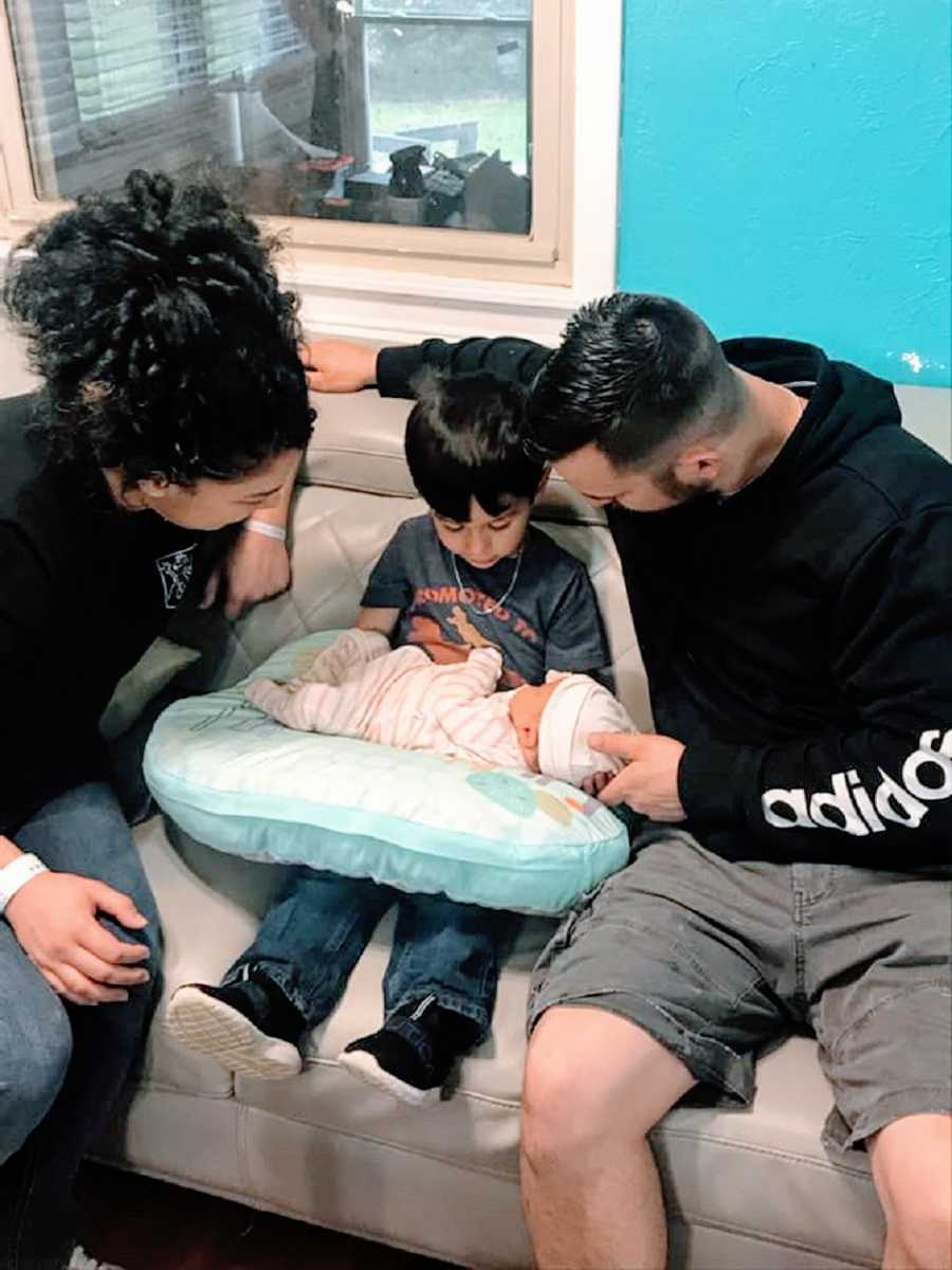 Parents sit with their young son and newborn baby