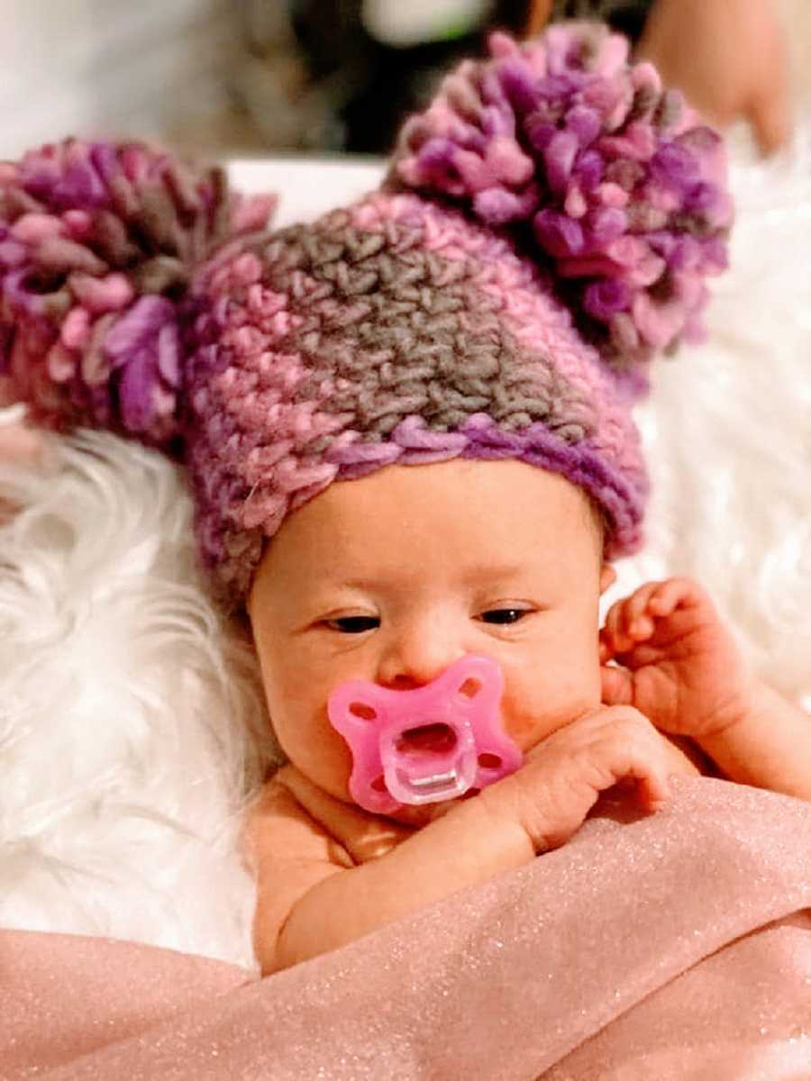 A little girl with a pacifier and a knit hat