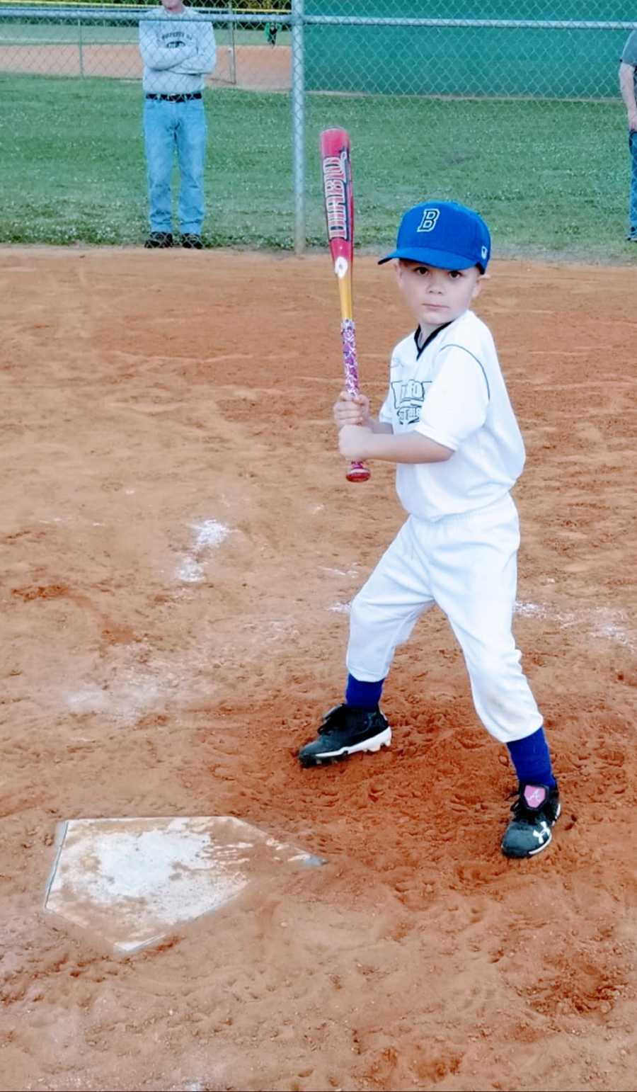 A little boy stands at home plate holding a bat