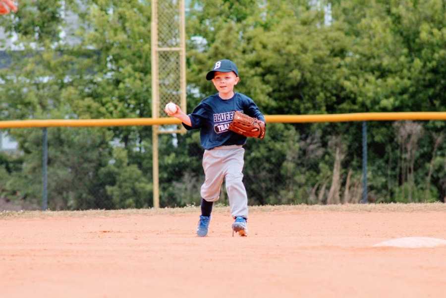 A little boy fields a ball in a t-ball game