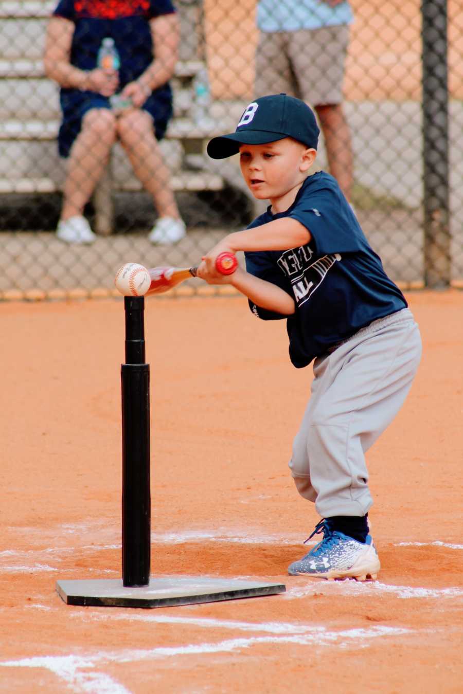 A little boy swings a bat at a ball on a tee