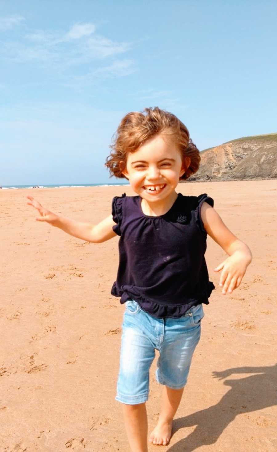 A young girl runs on a beach