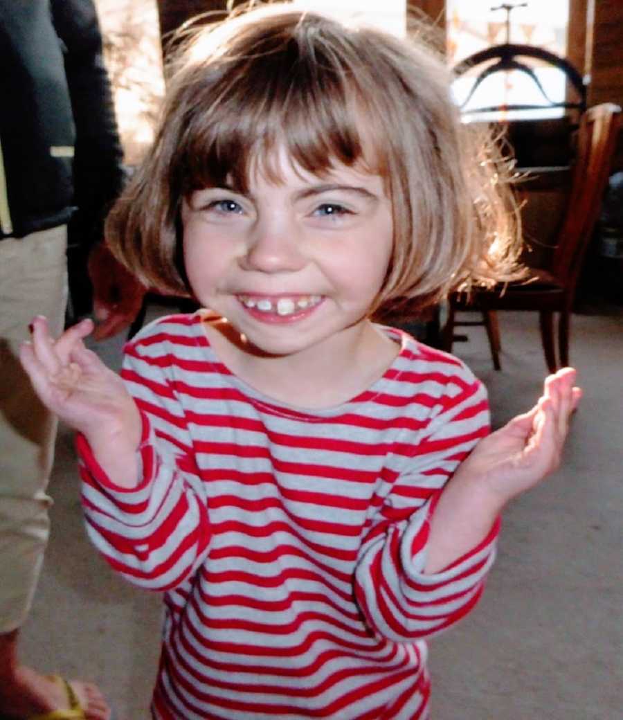 A girl wearing a striped shirt shrugs and giggles