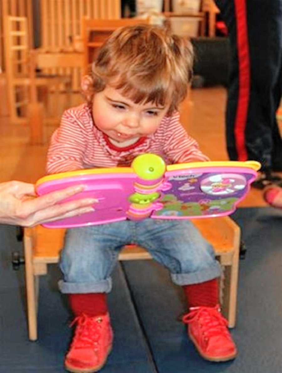 A little girl sits and plays with a toy book