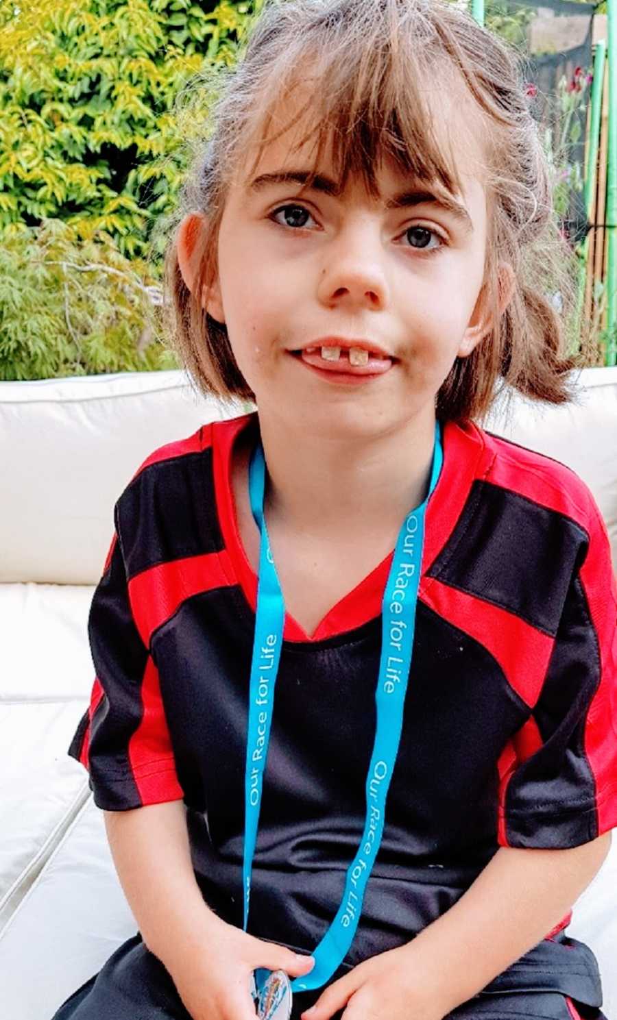 A girl wearing a lanyard sticks her tongue out at the camera