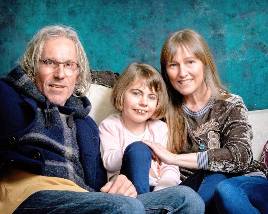 Parents sit with their daughter on a couch