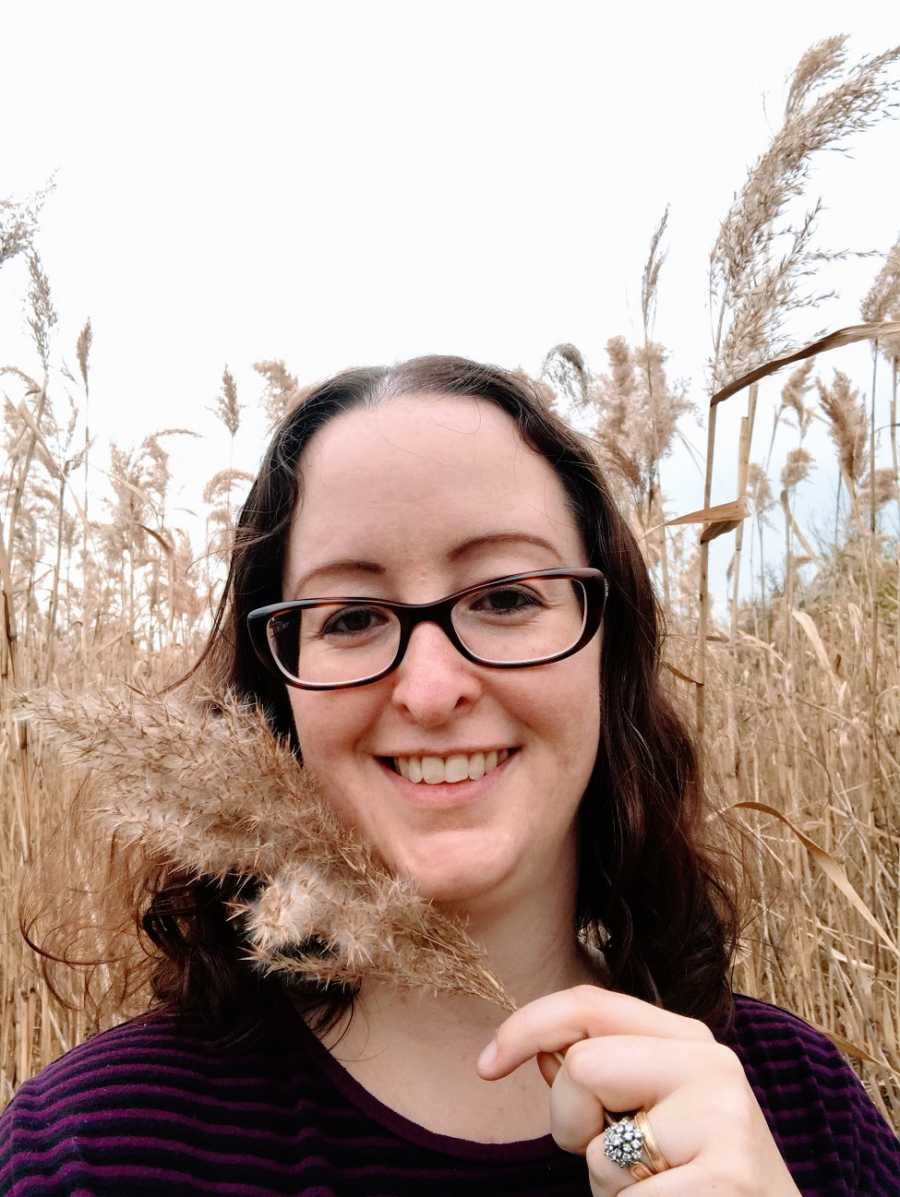 A woman stands in a field of tall grass