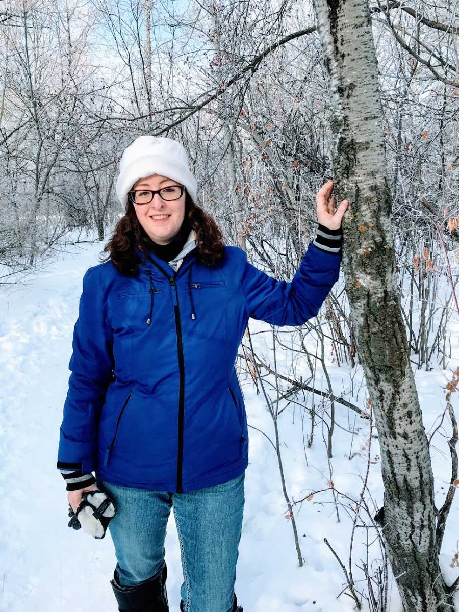 A woman stands in the woods in the snow