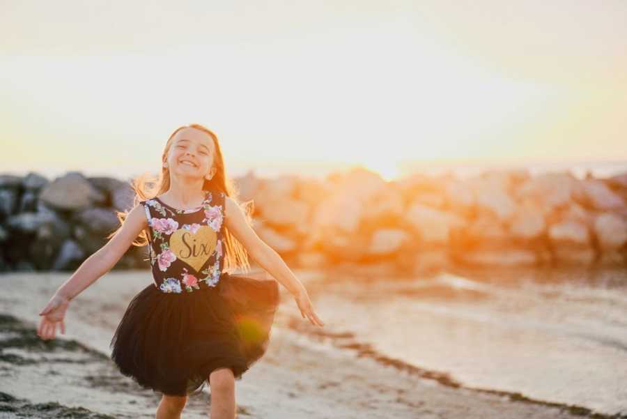 A little girl on a beach wearing a black skirt