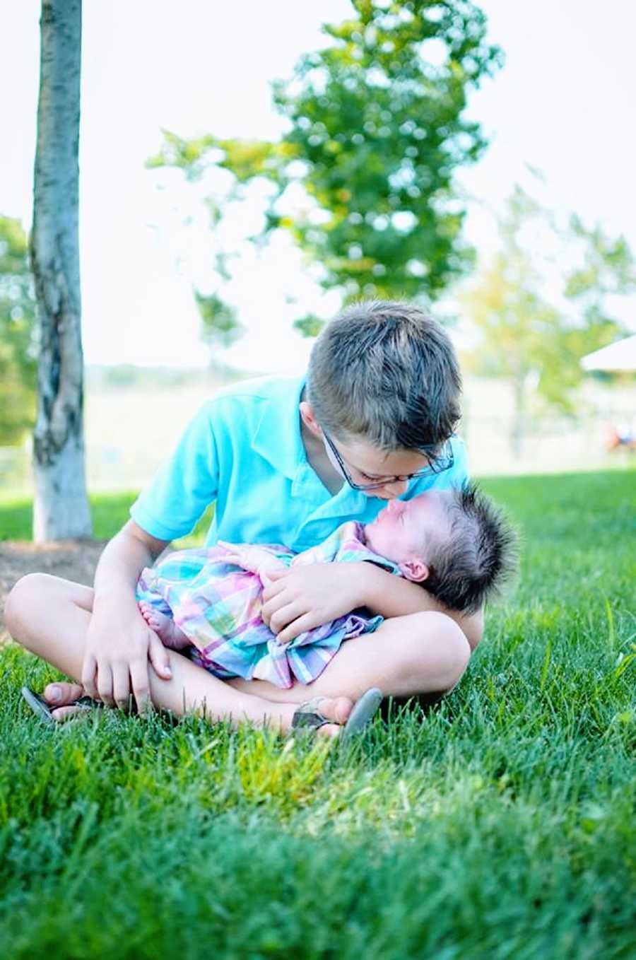 A boy kisses his baby sister on the nose