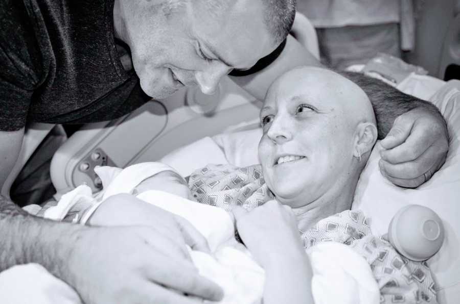 A mother and father hold their newborn baby girl