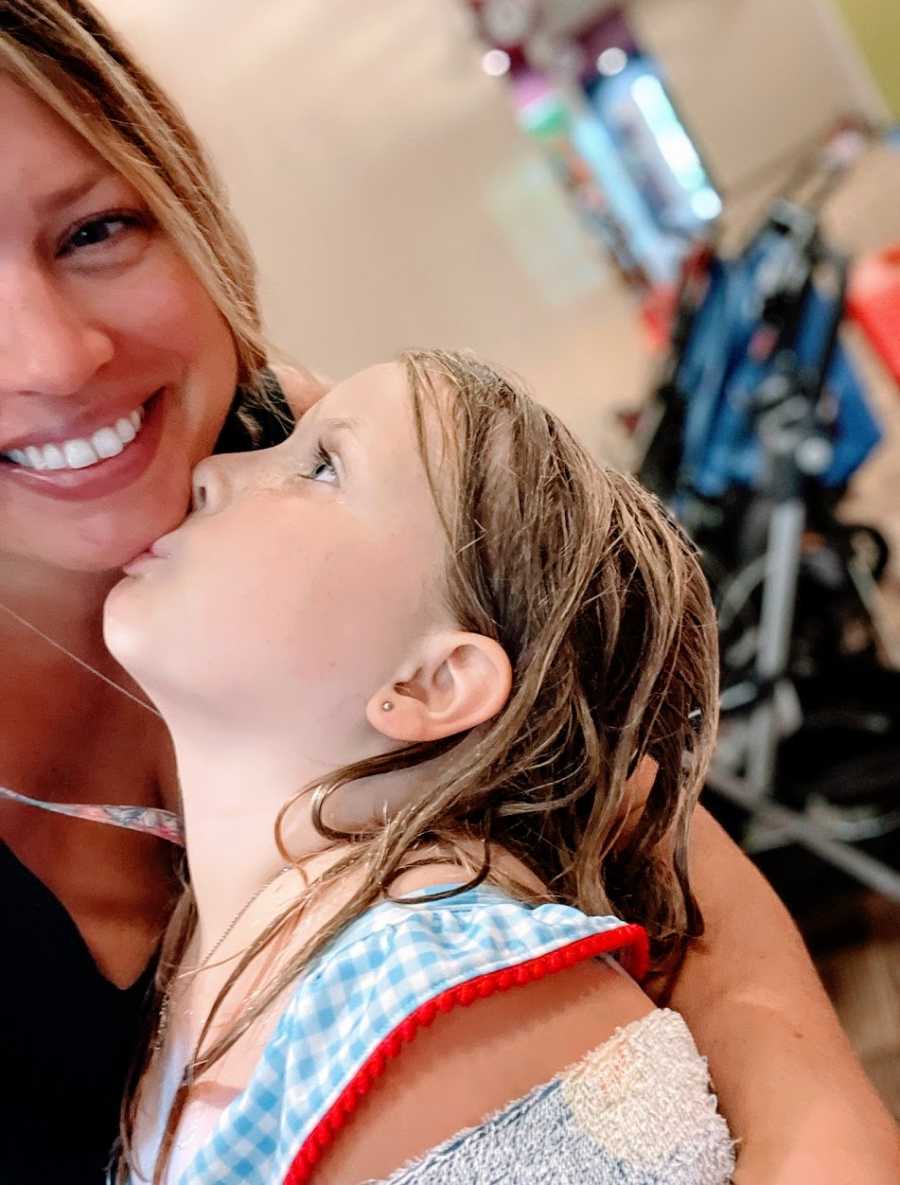 A little girl kisses her mom on the chin