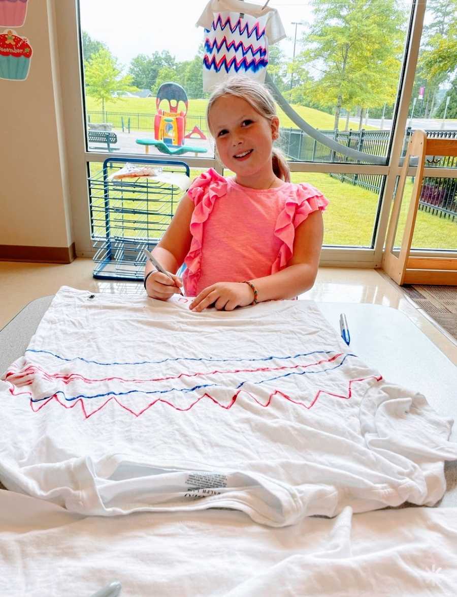 A young girl wearing a pink shirt sits at a table