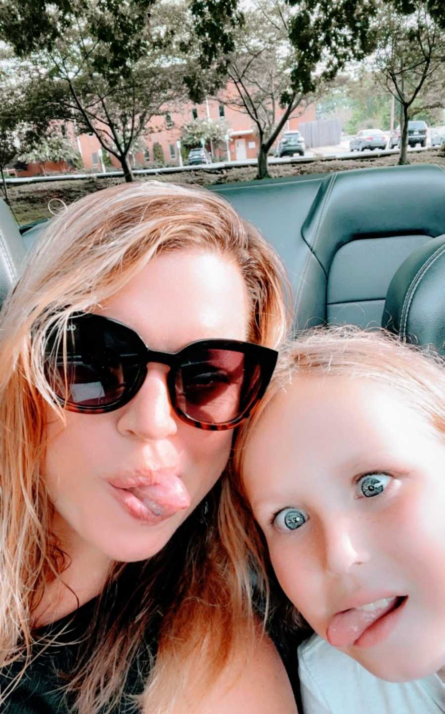 A mom and her daughter make silly faces in their car