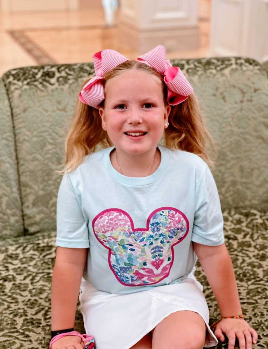 A little girl wearing bows in her hair and a Mickey Mouse shirt