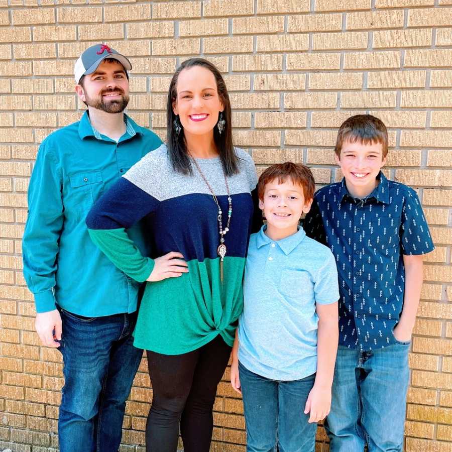 A woman stands with her husband and two sons